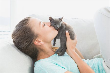 Cheerful woman lying on sofa kissing a grey kitten at home in the living room Stock Photo - Budget Royalty-Free & Subscription, Code: 400-07474368
