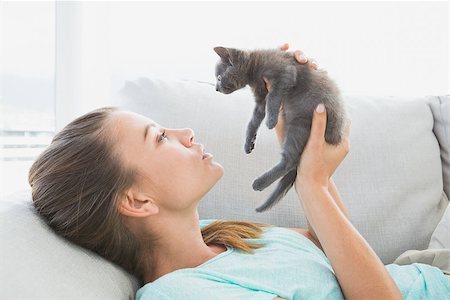 Cheerful woman lying on sofa holding a grey kitten at home in the living room Stock Photo - Budget Royalty-Free & Subscription, Code: 400-07474369