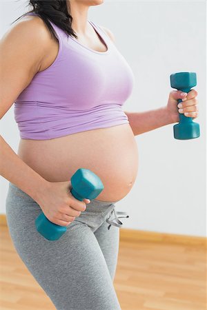 simsearch:400-06690931,k - Pregnant brunette holding dumbbells in a fitness studio Fotografie stock - Microstock e Abbonamento, Codice: 400-07474414