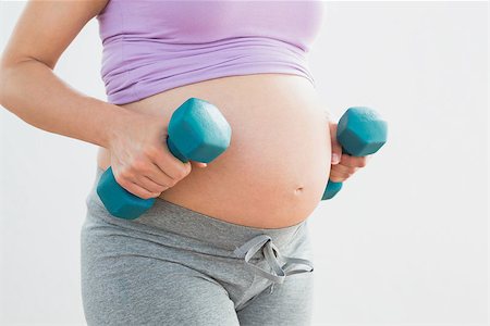 simsearch:400-06690931,k - Pregnant woman holding dumbbells in a fitness studio Fotografie stock - Microstock e Abbonamento, Codice: 400-07474415