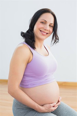 simsearch:400-06690931,k - Happy pregnant brunette smiling at camera in a fitness studio Fotografie stock - Microstock e Abbonamento, Codice: 400-07474413