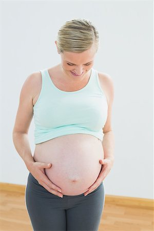 simsearch:400-06690931,k - Blonde pregnant woman looking down at her belly in a fitness studio Fotografie stock - Microstock e Abbonamento, Codice: 400-07474455