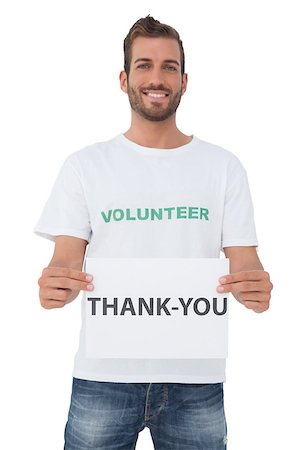 Smiling young male volunteer holding 'thank you' paper over white background Stockbilder - Microstock & Abonnement, Bildnummer: 400-07474808