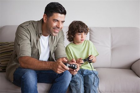 sofa two boys video game - Cheerful father and son playing video games in the living room at home Stock Photo - Budget Royalty-Free & Subscription, Code: 400-07475190