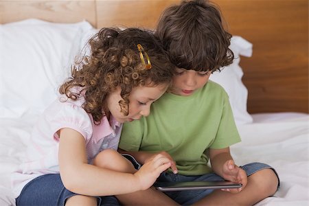 Young boy and girl using digital tablet in bed at home Stock Photo - Budget Royalty-Free & Subscription, Code: 400-07475226