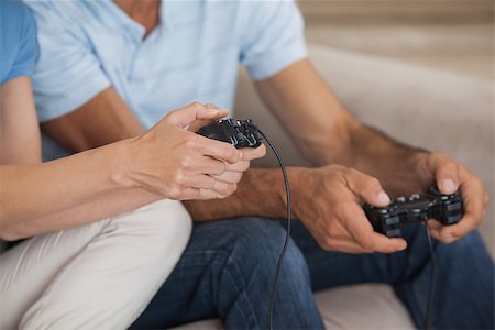 Close-up mid section of a couple playing video games in the living room at home Stock Photo - Budget Royalty-Free & Subscription, Code: 400-07475288