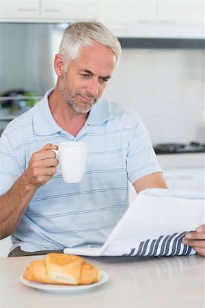 simsearch:6113-07906204,k - Happy man reading the newspaper at breakfast at home in the kitchen Stockbilder - Microstock & Abonnement, Bildnummer: 400-07475767