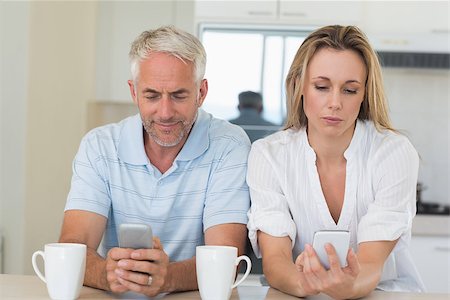 Distant couple sitting at the counter texting and not talking at home in the kitchen Stock Photo - Budget Royalty-Free & Subscription, Code: 400-07475782
