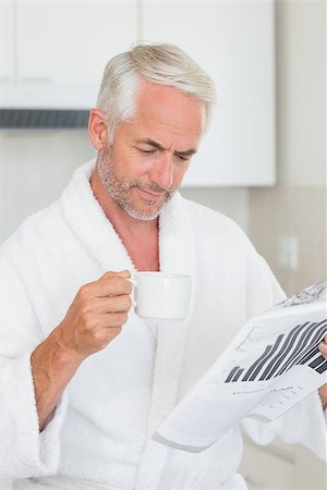 simsearch:400-06871178,k - Happy man reading newspaper at breakfast in a bathrobe at home in the kitchen Stock Photo - Budget Royalty-Free & Subscription, Code: 400-07475865