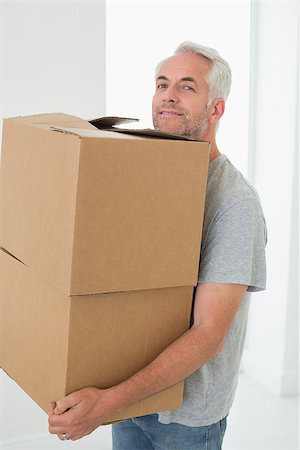 simsearch:400-07928013,k - Smiling man carrying cardboard moving boxes in new home Fotografie stock - Microstock e Abbonamento, Codice: 400-07475964