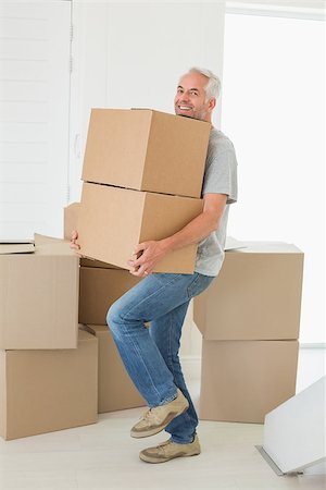 simsearch:400-07928013,k - Smiling man carrying cardboard moving boxes in new home Fotografie stock - Microstock e Abbonamento, Codice: 400-07475965