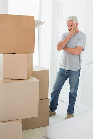 simsearch:400-07928013,k - Thoughtful man looking at cardboard moving boxes in new home Fotografie stock - Microstock e Abbonamento, Codice: 400-07475970