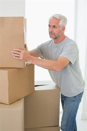 simsearch:400-07928013,k - Thoughtful man looking at cardboard moving boxes in new home Fotografie stock - Microstock e Abbonamento, Codice: 400-07475972