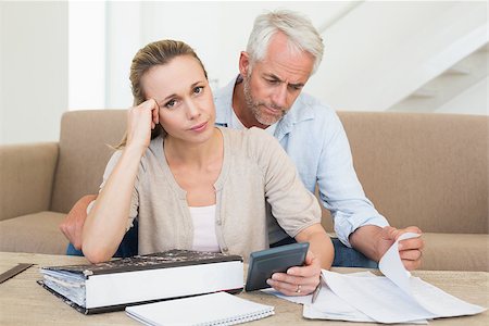 simsearch:400-07333928,k - Serious couple calculating their bills at the couch at home in the living room Stock Photo - Budget Royalty-Free & Subscription, Code: 400-07476034