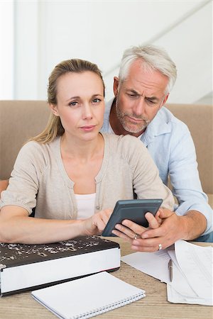 simsearch:400-07333928,k - Serious couple calculating their bills at the couch at home in the living room Stock Photo - Budget Royalty-Free & Subscription, Code: 400-07476036