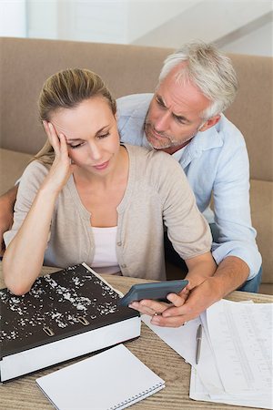 simsearch:400-07333928,k - Serious couple calculating their bills at the couch at home in the living room Stock Photo - Budget Royalty-Free & Subscription, Code: 400-07476038