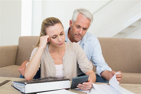 simsearch:400-07333928,k - Serious couple calculating their bills at the couch at home in the living room Stock Photo - Budget Royalty-Free & Subscription, Code: 400-07476033