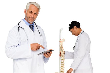 doctor bone model - Portrait of  male doctor holding digital table with colleague by skeleton model over white background Stock Photo - Budget Royalty-Free & Subscription, Code: 400-07476229