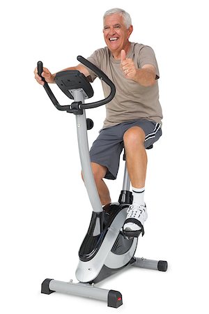 Full length of a senior man gesturing thumbs up on stationary bike over white background Stock Photo - Budget Royalty-Free & Subscription, Code: 400-07476301
