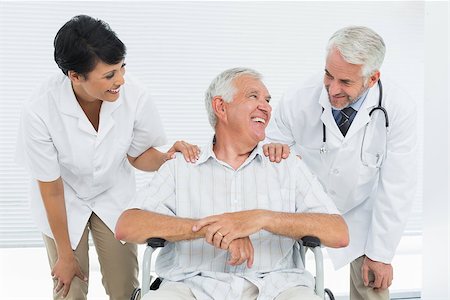 Happy senior patient with doctors sitting in wheelchair at the hospital Fotografie stock - Microstock e Abbonamento, Codice: 400-07476522