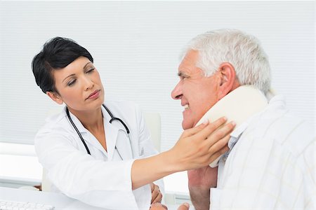 simsearch:400-07269643,k - Close-up of a female doctor examining a senior patients neck at medical office Fotografie stock - Microstock e Abbonamento, Codice: 400-07476561