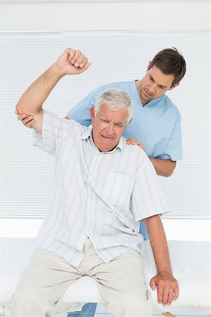 simsearch:400-07335332,k - Male physiotherapist assisting senior man to raise hand in the medical office Fotografie stock - Microstock e Abbonamento, Codice: 400-07476594