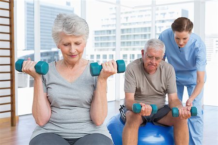 simsearch:400-07335332,k - Female therapist assisting senior couple with dumbbells in the medical office Fotografie stock - Microstock e Abbonamento, Codice: 400-07476648