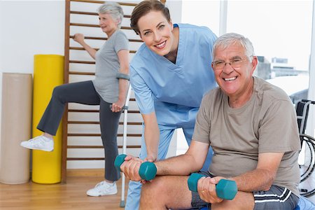 simsearch:400-07335332,k - Female therapist assisting senior man with dumbbells in the medical office Fotografie stock - Microstock e Abbonamento, Codice: 400-07476641