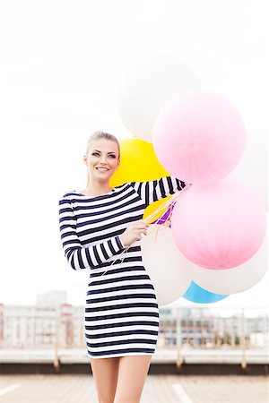 simsearch:400-07506274,k - beautiful smiling girl with ponytail hair in short black and white striped dress and white high sneakers holds bunch of multicolored balloons Fotografie stock - Microstock e Abbonamento, Codice: 400-07477484