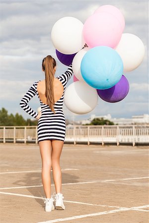 simsearch:400-07506274,k - back view of girl in open-back black and white striped short dress and white high top sneakers holds a bunch of multicolored balloons Photographie de stock - Aubaine LD & Abonnement, Code: 400-07477494