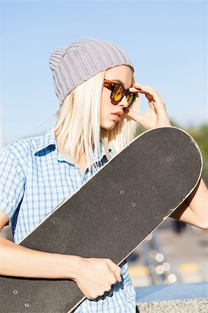 simsearch:400-07506274,k - Close-up of beautiful blond girl in beanie hat skateboard adjusting her leopard sunglasses on sunny day in the street Fotografie stock - Microstock e Abbonamento, Codice: 400-07477502