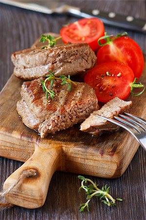 simsearch:400-08495308,k - Juicy beef steak with tomato salad served on an old wooden cutting board. Stockbilder - Microstock & Abonnement, Bildnummer: 400-07477668