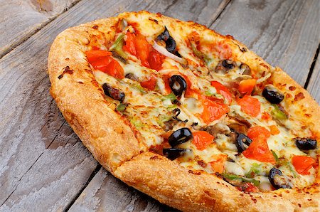 simsearch:400-07420117,k - Freshly Baked Vegetarian Pizza with Tomatoes, Black Olives and Cheese closeup on Rustic Wooden background Stock Photo - Budget Royalty-Free & Subscription, Code: 400-07478285