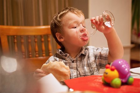 Young boy enjoying lunch draining the last drops of liquid from a glass as he holds a pie in his other hand Photographie de stock - Aubaine LD & Abonnement, Code: 400-07479515