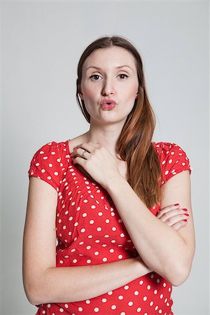 pursed - Studio portrait of attractive woman wearing spotty red blouse with pursed lips blowing kiss Stock Photo - Budget Royalty-Free & Subscription, Code: 400-07470194