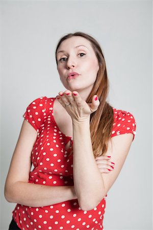 pursed - Studio portrait of attractive woman wearing spotty red blouse with pursed lips blowing a kiss Stock Photo - Budget Royalty-Free & Subscription, Code: 400-07470195