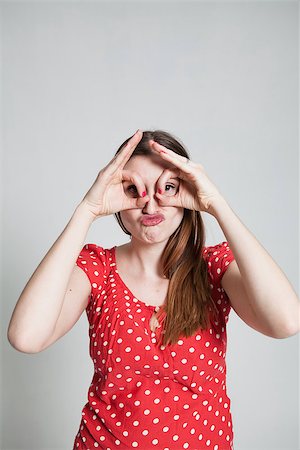 pursed - Studio portrait of attractive woman with pursed lips looking through finger goggles Stock Photo - Budget Royalty-Free & Subscription, Code: 400-07470199