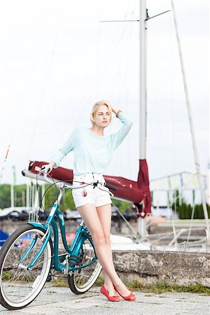 pretty tall blonde girl in short white shorts, transparent top with cruiser bike adjusts her hair at sea pier against yachts Stock Photo - Budget Royalty-Free & Subscription, Code: 400-07470652