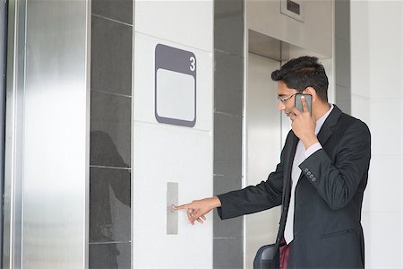 Asian Indian businessman pressing on elevator button, waiting door open to enter inside the lift. Stock Photo - Budget Royalty-Free & Subscription, Code: 400-07470856
