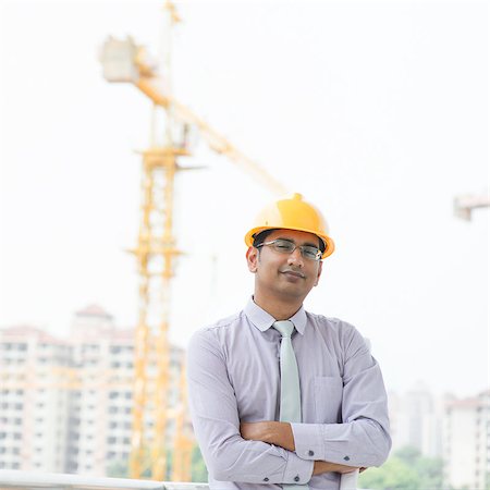 engineer background - Portrait of a smiling Asian Indian male contractor engineer with hard hat standing in front construction site. Stock Photo - Budget Royalty-Free & Subscription, Code: 400-07470861