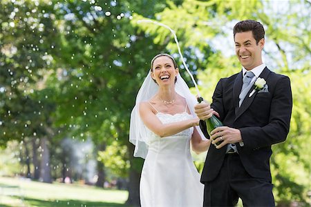 simsearch:400-07473236,k - Young newlywed couple popping cork of champagne in park Stockbilder - Microstock & Abonnement, Bildnummer: 400-07473234