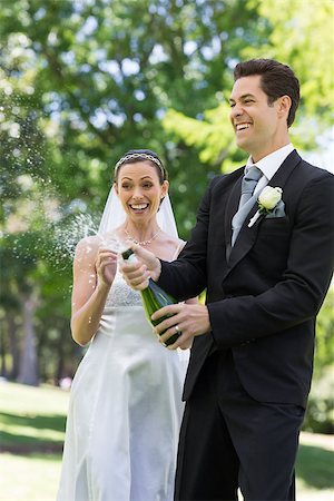 simsearch:400-07473236,k - Young newlywed couple popping cork of champagne in park Stockbilder - Microstock & Abonnement, Bildnummer: 400-07473236