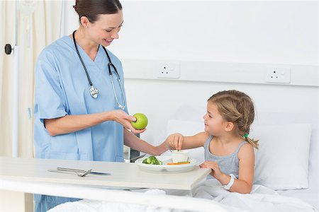 simsearch:400-07473471,k - Smiling doctor giving apple to sick girl in hospital ward Photographie de stock - Aubaine LD & Abonnement, Code: 400-07473375