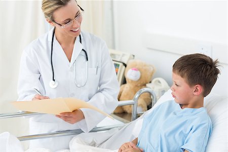 simsearch:400-06734647,k - Happy female doctor examining report of sick boy in hospital Stock Photo - Budget Royalty-Free & Subscription, Code: 400-07473480