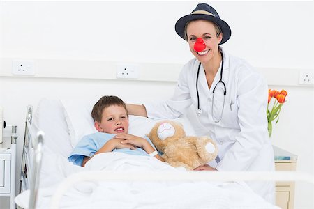 Portrait of happy female doctor in clown costume with sick boy in hospital bed Stock Photo - Budget Royalty-Free & Subscription, Code: 400-07473497
