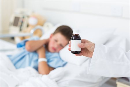 simsearch:400-07473471,k - Closeup of doctor holding bottle of cough syrup with sick boy in hospital bed Photographie de stock - Aubaine LD & Abonnement, Code: 400-07473490