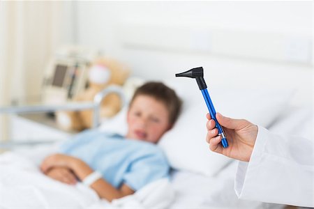 simsearch:400-07473471,k - Closeup of doctor holding otoscope with sick boy in hospital bed Photographie de stock - Aubaine LD & Abonnement, Code: 400-07473493