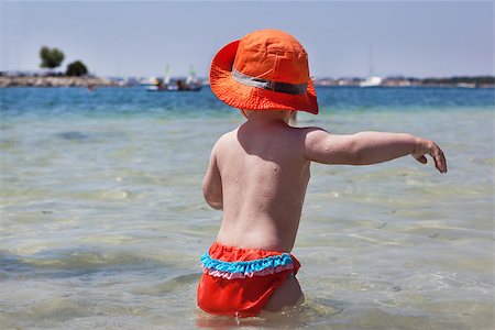 Little baby girl in a orange hat and bathing suit splashing in the sea Stock Photo - Budget Royalty-Free & Subscription, Code: 400-07480450