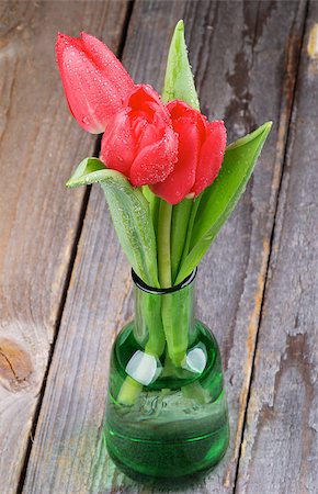 smelling tulip - Three Spring Red Tulips with Water Drops in Green Bottle isolated on Rustic Wooden background Stock Photo - Budget Royalty-Free & Subscription, Code: 400-07481068