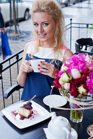 a beautiful young blond girl with blue eyes and toothy smile at the table in pavement cafe is holding a tea cup Stock Photo - Budget Royalty-Free & Subscription, Code: 400-07481371